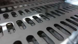Close-up of polished stainless steel surface with oval perforations for industrial use