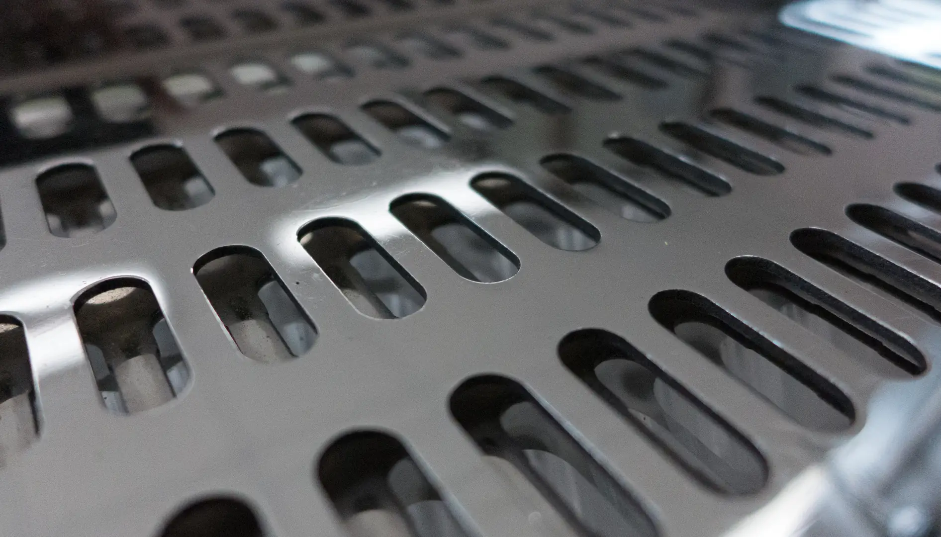 Close-up of polished stainless steel surface with oval perforations for industrial use